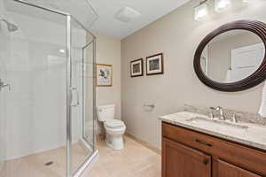 Bathroom featuring tile patterned floors, vanity, toilet, and an enclosed shower