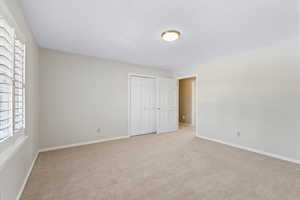 Unfurnished bedroom featuring a closet, light colored carpet, and a textured ceiling