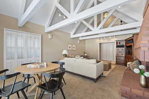 Carpeted living room with beamed ceiling and high vaulted ceiling