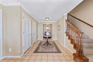 Foyer entrance featuring crown molding and light tile patterned floors