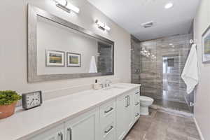 Bathroom with vanity, a shower with shower door, a textured ceiling, and toilet