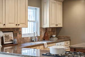 Kitchen featuring white dishwasher, tasteful backsplash, sink, and cream cabinets