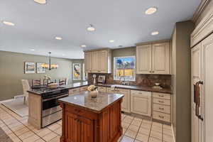 Kitchen featuring kitchen peninsula, decorative light fixtures, a kitchen island, and stainless steel range with gas stovetop