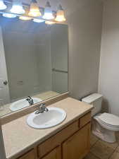 Bathroom featuring tile patterned flooring, vanity, toilet, and walk in shower