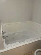 Bathroom featuring tile patterned floors, toilet, and a bath