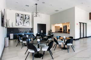 Dining space with a notable chandelier, visible vents, a high ceiling, and baseboards