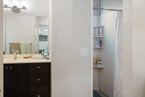 Bathroom featuring a shower with shower curtain and vanity