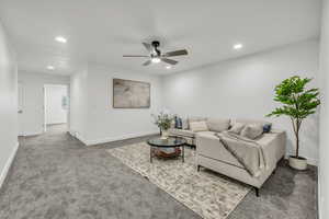 Carpeted living area with baseboards, ceiling fan, and recessed lighting