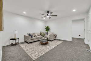 Carpeted living area featuring recessed lighting, visible vents, and baseboards