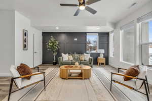 Living room with light wood-type flooring, visible vents, a decorative wall, and baseboards