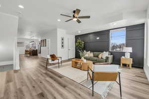 Living area with light wood-style floors, plenty of natural light, and a decorative wall