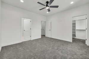 Unfurnished bedroom featuring baseboards, a walk in closet, carpet floors, a closet, and recessed lighting