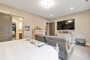 Carpeted bedroom featuring a barn door, a textured ceiling, and ensuite bath