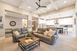 Living room with beamed ceiling, ceiling fan, light carpet, and coffered ceiling