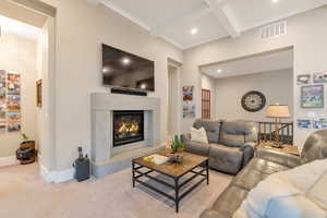 Living room featuring beam ceiling, crown molding, light colored carpet, and coffered ceiling