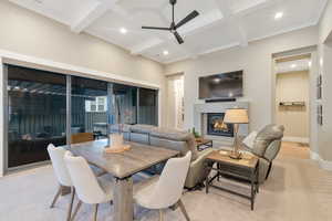 Carpeted dining room featuring beamed ceiling, ceiling fan, crown molding, and coffered ceiling