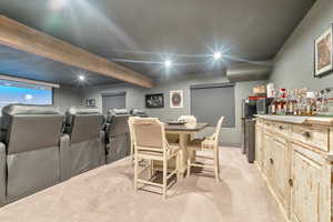 Dining room featuring beamed ceiling, indoor bar, and light colored carpet