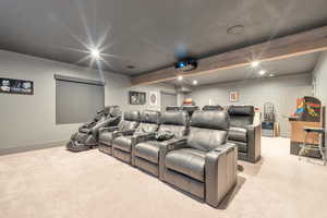 Carpeted cinema featuring beamed ceiling