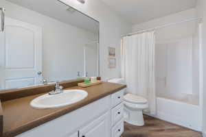 Full bathroom with hardwood / wood-style flooring, vanity, toilet, and shower / tub combo with curtain