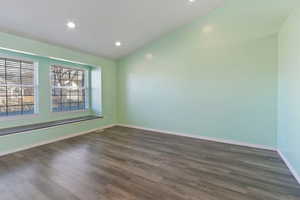 Unfurnished room featuring lofted ceiling and dark hardwood / wood-style floors