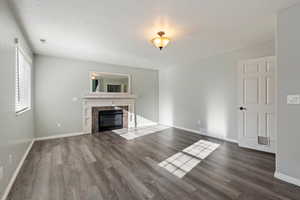 Unfurnished living room featuring a textured ceiling, dark wood-type flooring, and a tiled fireplace