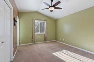 Unfurnished bedroom with ceiling fan, a closet, light carpet, and lofted ceiling