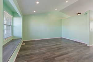 Unfurnished room with dark hardwood / wood-style floors and vaulted ceiling