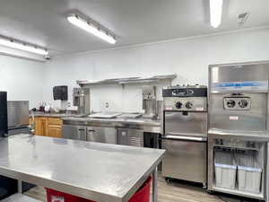 Kitchen with white cabinetry, stainless steel counters, and light hardwood / wood-style flooring