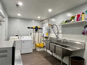 Washroom featuring independent washer and dryer, tankless water heater, and dark wood-type flooring