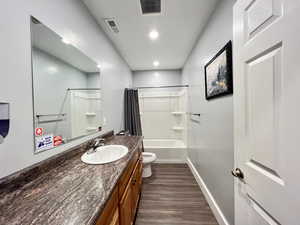 Full bathroom with shower / bath combo, vanity, toilet, and wood-type flooring