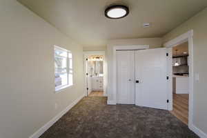 Unfurnished bedroom featuring carpet flooring, ensuite bathroom, a closet, and sink