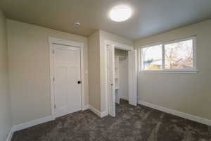 Unfurnished bedroom with dark colored carpet and a closet