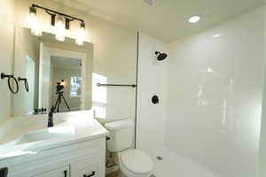 Bathroom with tiled shower, vanity, and toilet