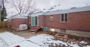 Snow covered back of property featuring central AC unit