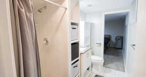 Bathroom with tile patterned flooring, vanity, curtained shower, and toilet