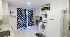 Kitchen with white cabinetry, sink, and white appliances