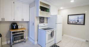 Kitchen with butcher block countertops, white cabinets, and white appliances