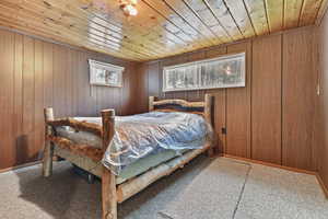 Bedroom featuring wood walls, wood ceiling, and carpet floors