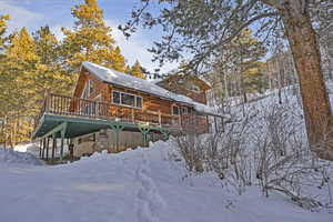 Snow covered back of property with a wooden deck