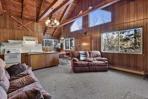 Living room featuring carpet, beam ceiling, an inviting chandelier, and baseboard heating