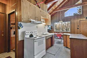 Kitchen with sink, exhaust hood, beam ceiling, electric range, and wood walls