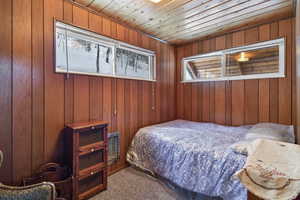 Bedroom with carpet, wood walls, and wood ceiling