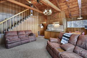 Living room with carpet, wooden walls, beamed ceiling, and wooden ceiling