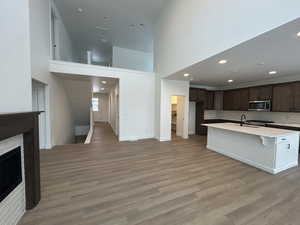 Kitchen with a breakfast bar, dark brown cabinets, stainless steel appliances, a high ceiling, and an island with sink