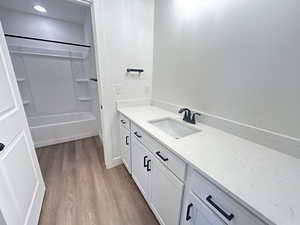 Bathroom with vanity, wood-type flooring, and shower / bathtub combination