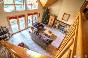 Carpeted living room with french doors, wooden ceiling, high vaulted ceiling, and a stone fireplace