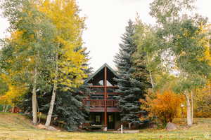 Back of property featuring a lawn and a deck