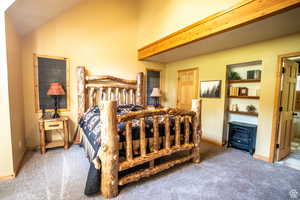 Bedroom featuring ensuite bath, carpet, and lofted ceiling