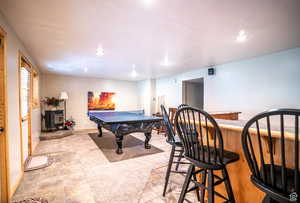 Playroom with bar, a wood stove, and light tile patterned flooring