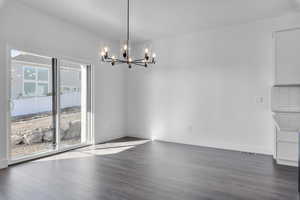 Unfurnished dining area with dark hardwood / wood-style flooring and an inviting chandelier